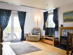 sala de estar con TV y silla en The Boat House en Lochmaddy