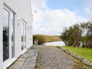 une maison blanche avec vue sur une étendue d'eau dans l'établissement The Boat House, à Lochmaddy