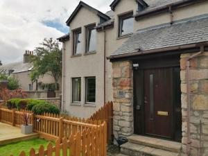 una casa con una valla de madera y una puerta de madera en Riverside View en Nairn