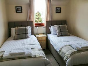 2 camas en una habitación pequeña con ventana en Riverside View en Nairn