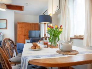 uma mesa de jantar com um vaso e flores em The Stables em Clyst Saint Mary