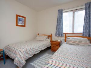 2 camas individuales en un dormitorio con ventana en The Stables, en Clyst Saint Mary