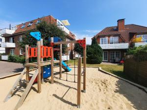 un parque infantil en la arena frente a una casa en Residenz Vogelsand 1, en Cuxhaven
