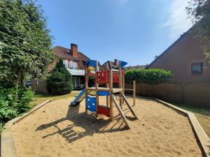 un parque infantil en la arena en un patio en Residenz Vogelsand 1, en Cuxhaven