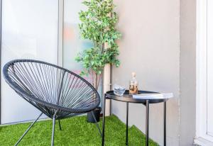 una silla y una mesa en el césped junto a una planta en CAOPEO - Top Hôte Paris - 8 personnes Balcon Parking, en Saint-Denis