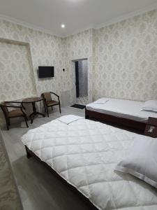 1 dormitorio con 2 camas, mesa y TV en Comfort Tashkent, en Tashkent