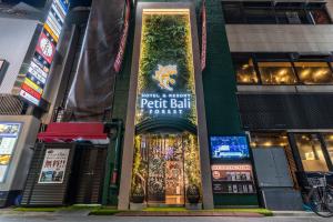 a building with a sign on the front of it at Petit Bali Forest Shinjuku Sanchōme in Tokyo