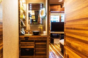 a bathroom with a sink and a desk with a television at Petit Bali Forest Shinjuku Sanchōme in Tokyo