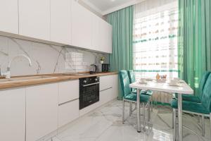 cocina con armarios blancos, mesa y sillas en Salem, en Zaozërnyy