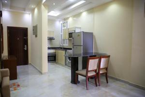 a kitchen with a table and two chairs and a refrigerator at Park Complex in Salalah