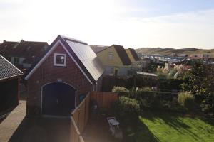 a small brick house with a garage in a yard at Strandhuisje achter de duinen. in Julianadorp