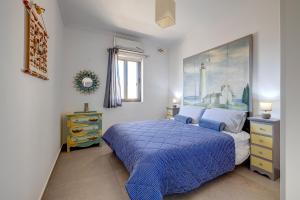 a bedroom with a blue bed and a painting on the wall at Perfect Location Idyllic 2BR Apartment in Sliema