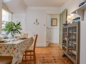 a dining room with a table and a cabinet at Shipwrights Cottage in Teignmouth