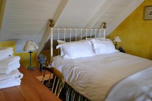 a bedroom with a white bed and a desk at Dullies Cottage in Dullstroom