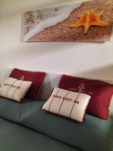 ein Bett mit roten und weißen Kissen und einem Bild in der Unterkunft Capo Ognina in Catania