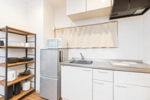 eine Küche mit einer Spüle und einem Kühlschrank in der Unterkunft Mita Guest House in Tokio
