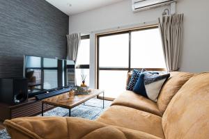 ein Wohnzimmer mit einem braunen Sofa und einem TV in der Unterkunft Mita Guest House in Tokio