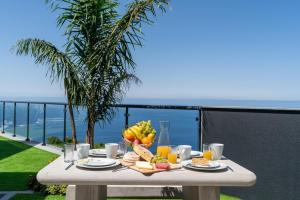 - une table avec un bol de fruits et de jus sur un balcon dans l'établissement OurMadeira - Sunset Cliff Villas, contemporary, à Fajã da Ovelha