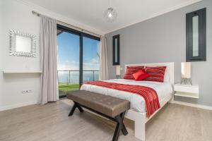 a white bedroom with a bed and a large window at OurMadeira - Sunset Cliff Villas, contemporary in Fajã da Ovelha