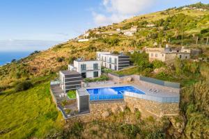 an aerial view of a house on a hill with a swimming pool at OurMadeira - Sunset Cliff Villas, contemporary in Fajã da Ovelha