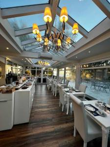 um restaurante com mesas e cadeiras brancas e um lustre em Strandhotel Lindequist em Ostseebad Sellin