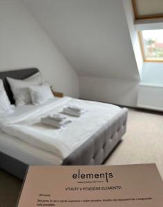a white bed with a sign in front of it at Penzión Elements in Trnava