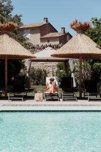 une femme assise sur une chaise à côté d'une piscine dans l'établissement Mas des Romarins, The Originals Relais, à Gordes