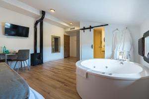 uma grande banheira branca num quarto com uma mesa em DUO SOMNIA, suites con jacuzzi y chimenea, only adults 