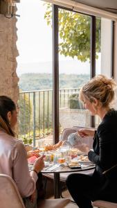 two women sitting at a table eating food at Mas des Romarins, The Originals Relais in Gordes
