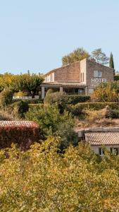 a building on top of a hill with trees at Mas des Romarins, The Originals Relais in Gordes