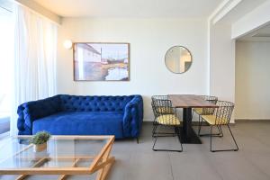 ein Wohnzimmer mit einem blauen Sofa und einem Tisch in der Unterkunft Life`s A Beach by HolyGuest in Tel Aviv
