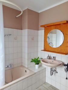 a bathroom with a tub and a sink and a mirror at Ferienwohnung Pasek in Mehlmeisel
