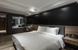 een slaapkamer met een groot wit bed en een badkamer bij Autumn Willow Hotel in Taichung