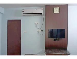een kamer met een televisie en een klok aan een muur bij Hotel Royal Palace, Begusarai in Durjanpur