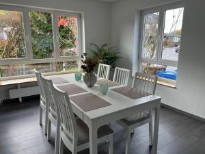 una mesa de comedor blanca con sillas y ventanas en Unique geräumige 4 Zimmer Wohnung in Tuttlingen mit Netflix, Sauna und Fitness, en Tuttlingen