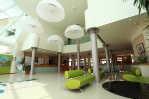 um hall de entrada do hospital com cadeiras verdes e luzes em Hotel Maregolf em Caorle