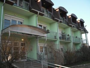 a green building with balconies on the side of it at Aba és Andrea Apartmanok in Sárvár