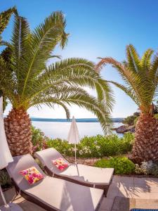 a patio with two chairs and palm trees and the ocean at Vila Klara Malinska in Porat