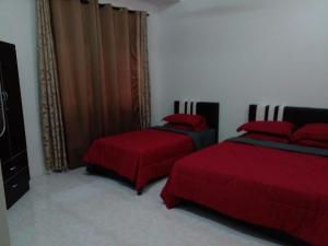 1 dormitorio con 2 camas con sábanas rojas en RZ Homestay en Kuala Terengganu