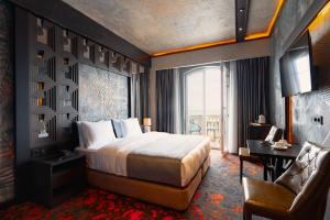 a hotel room with a bed and a desk and a chair at Tapis Rouge Design Boutique Hotel in Batumi