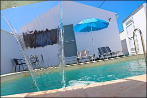 una fontana davanti a una piscina con un ombrellone blu di Chalet los Morenos a Conil de la Frontera