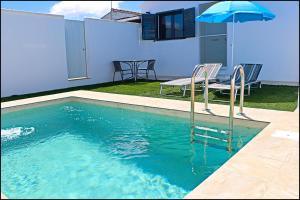una piscina con tavolo e ombrellone di Chalet los Morenos a Conil de la Frontera