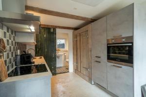 a kitchen with stainless steel appliances and wooden cabinets at Vakantiehuisje aan de rand van Arnhem in Arnhem