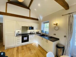 a kitchen with white cabinets and black counter tops at The Stable - For A Unique Retreat in Hooe