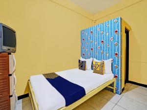 a bedroom with a bed with a blue headboard and a tv at OYO Life 91947 Kost Barokah Syariah in Mojokerto