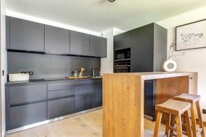 uma cozinha com armários cinzentos e um balcão com bancos em Sublime appartement 3 chambres avec 200m2 jardin em Megève