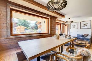 een eetkamer met een tafel en stoelen en een raam bij Sublime appartement 3 chambres avec 200m2 jardin in Megève