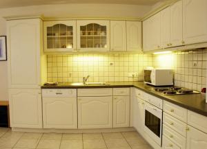 a kitchen with white cabinets and a sink at Landhaus am Golfplatz in Seefeld in Tirol