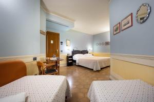 Cette chambre d'hôtel comprend deux lits, une table et des chaises. dans l'établissement Hotel San Luca, à Spolète