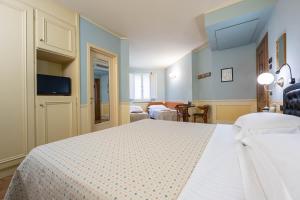 a bedroom with a white bed and a living room at Hotel San Luca in Spoleto